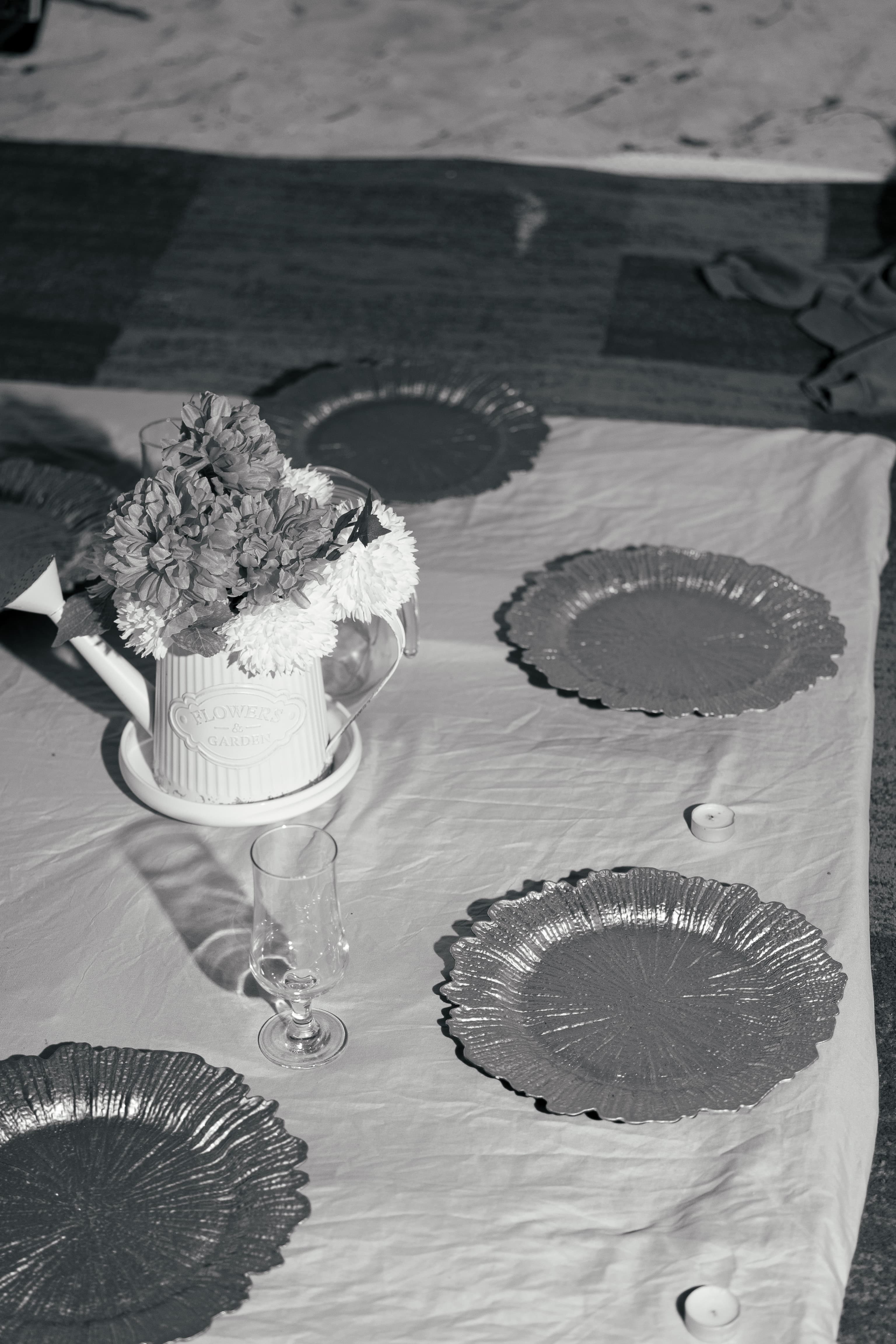 Black and white table setting featuring a watering can flower vase and textured plates.